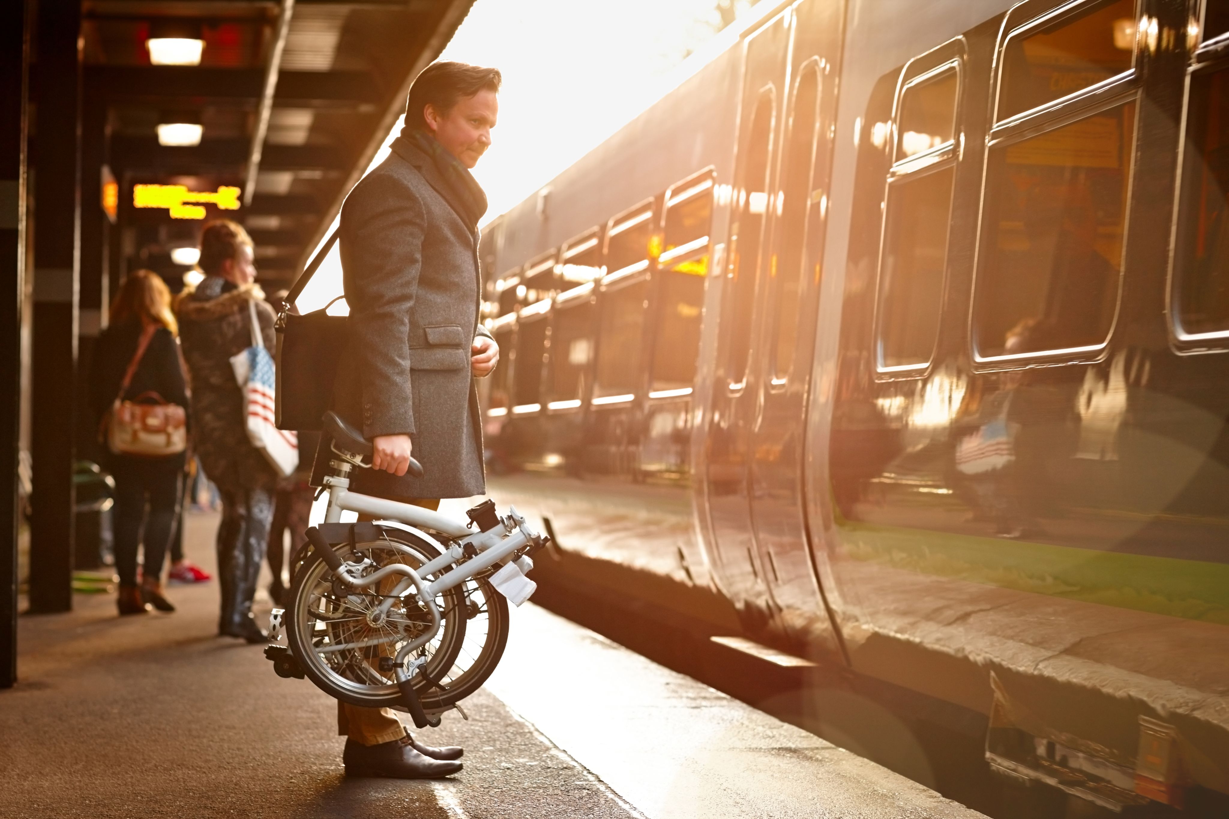 Man with fold up bike waiting to board a train