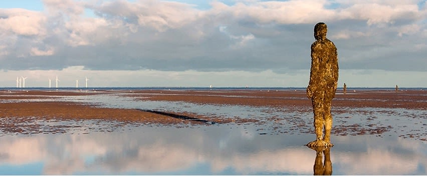 Antony Gormley’s sculpture looks out over the wind farm on Crosby beach near Liverpool.