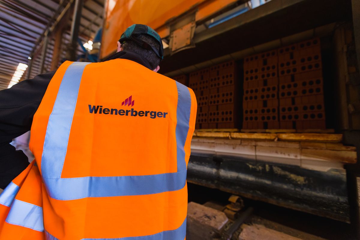 Wienerberger operator wearing a high visibility jacket standing in front of an open brick firing furnace with stacks of bricks inside