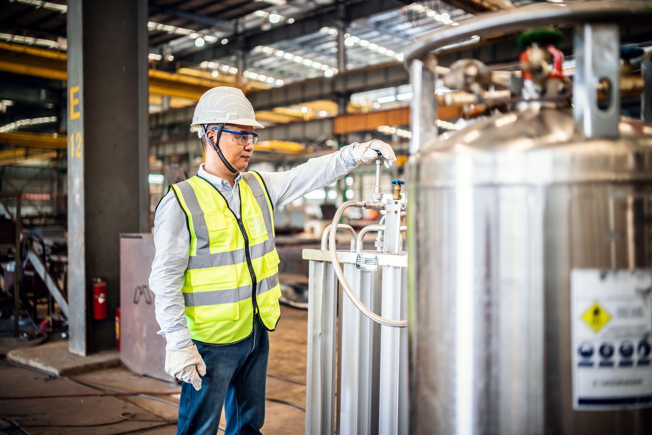 Asian worker operating a gas tank in a factory