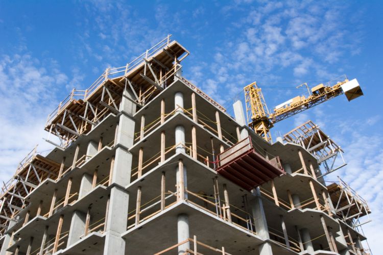 Reinforced steel & concrete building under construction. Safety guard rails, flyforms and tower crane