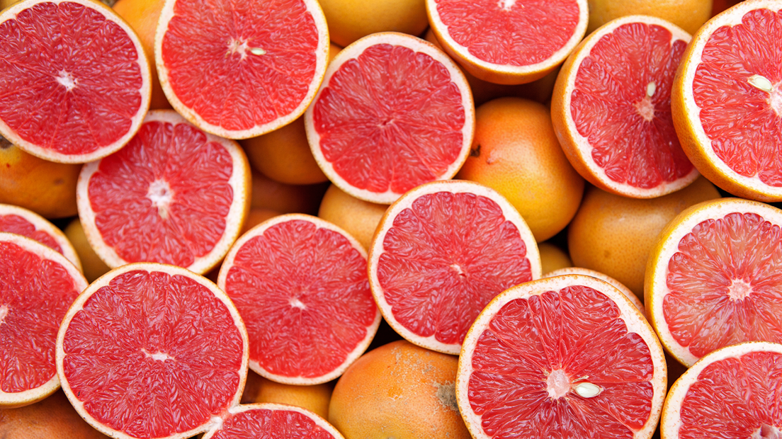 A spread of whole and halved pink grapefruits.