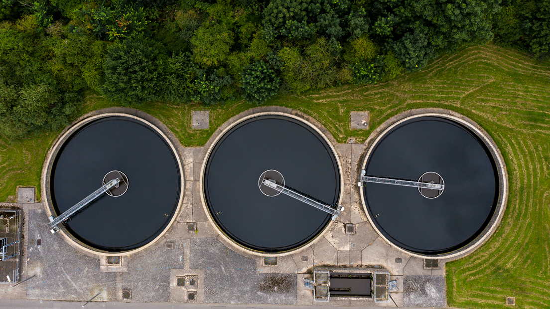 n aerial view of three tanks at a sewage of water treatment plant.