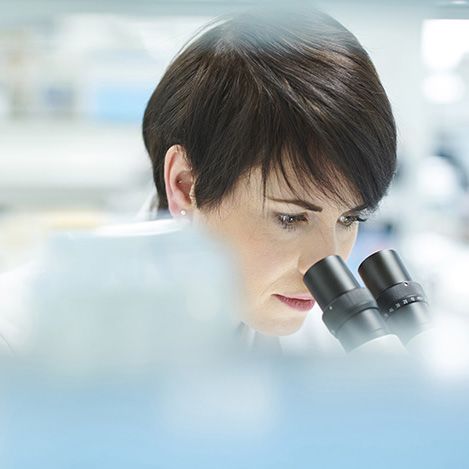 A female scientist in a research lab using a microscope.  