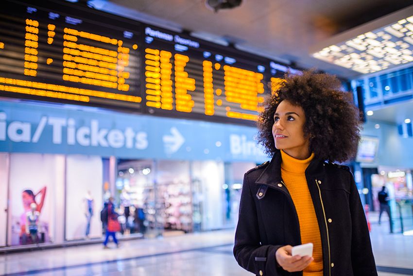 A woman at the airport by the departures board.