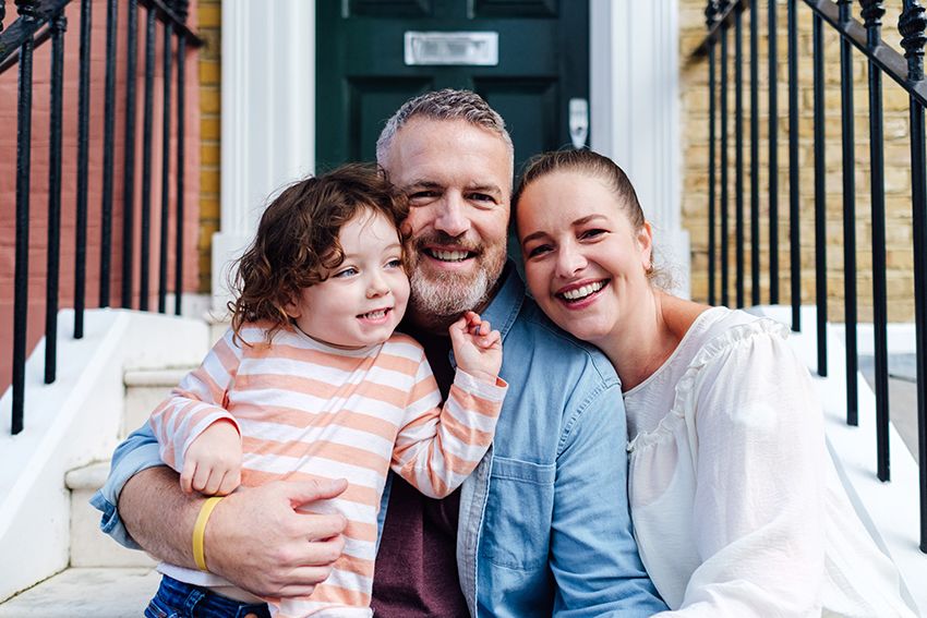 A portrait of family sitting on their front steps.