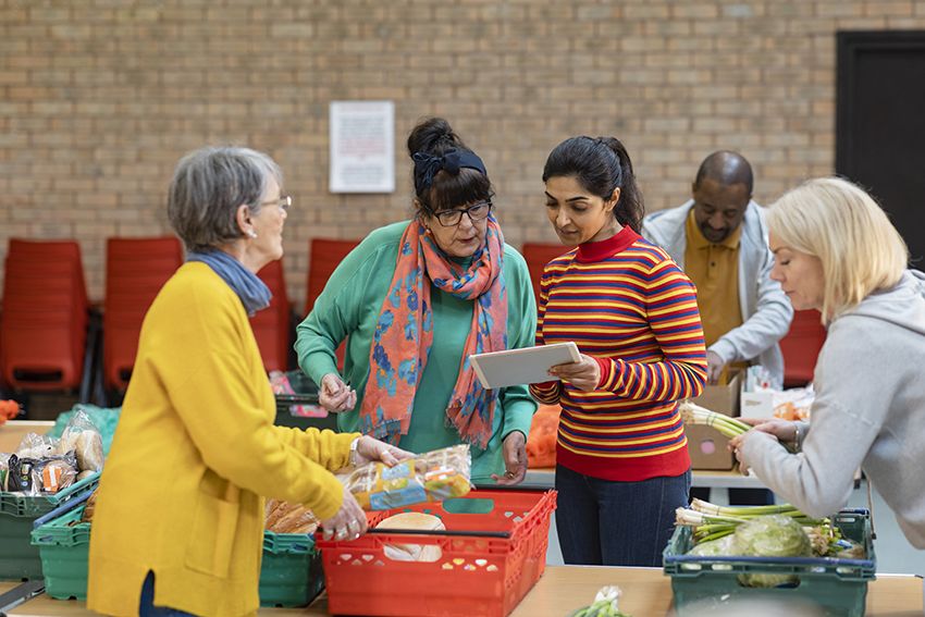 Group of volunteers organising food donations onto tables at a food bank.
