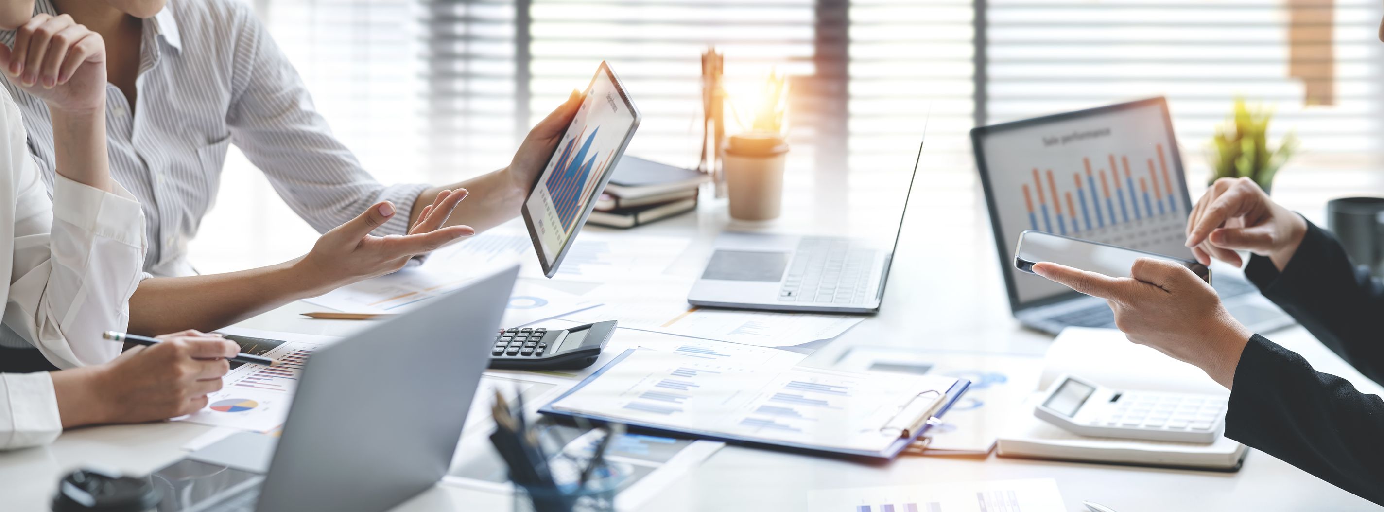 Two people discussing data on tablets and paper documents within a business office environment