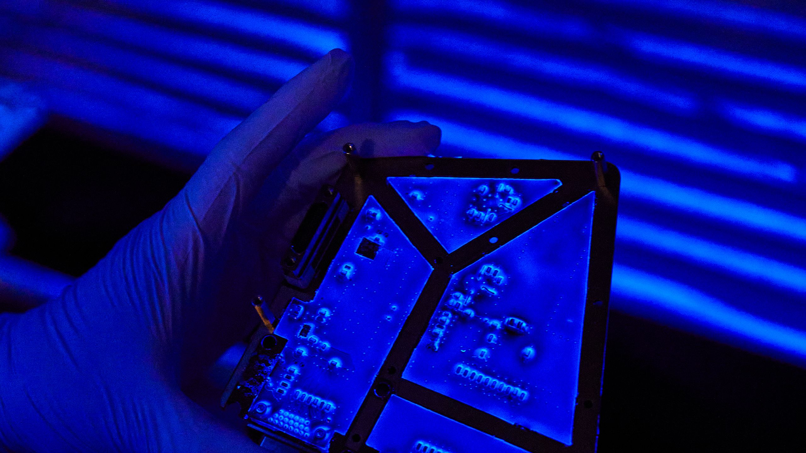 Printed circuit board undergoing conformal coating inspection under UV light.