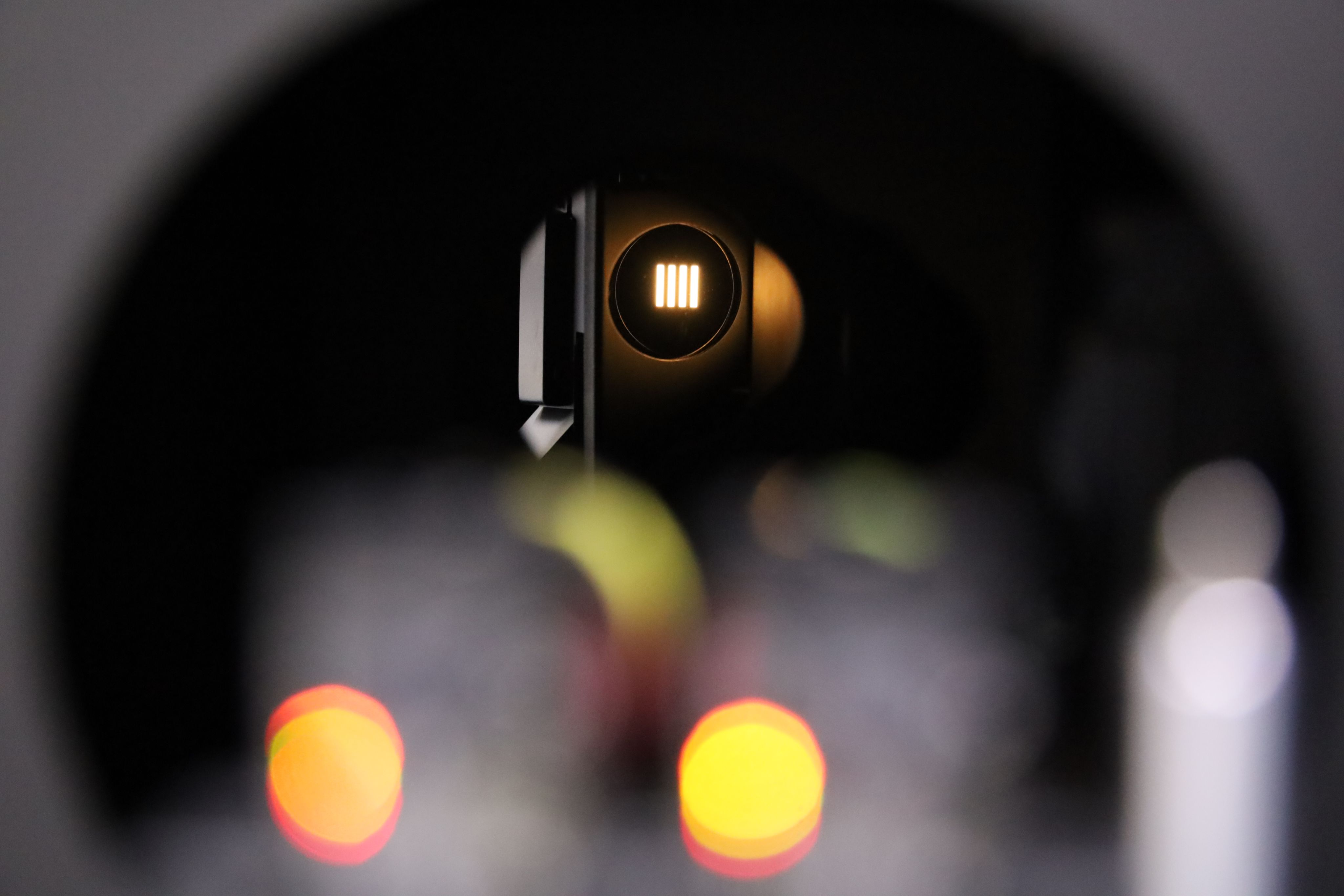 View inside one of the instruments used to calibrate instruments at the Small Satellite Calibration Facility. This is a long, dark tube with four bright lines of light at the far end.