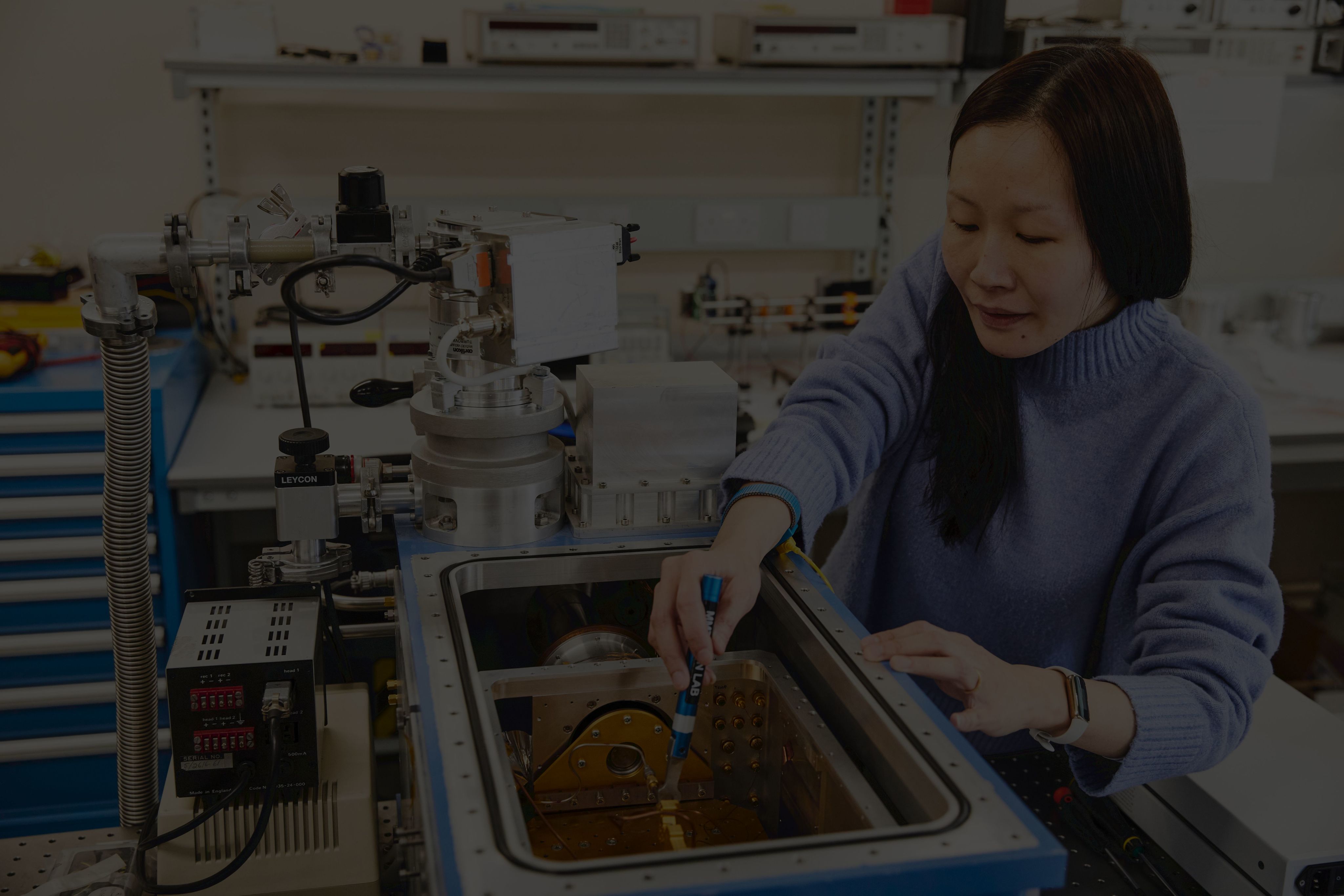A female scientist in the lab performing tests on an instrument.